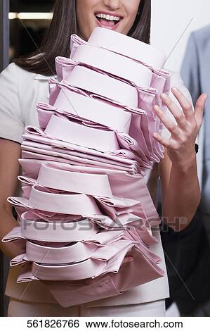 Stock Photograph - Saleswoman holding shirts in a clothing store. Fotosearch