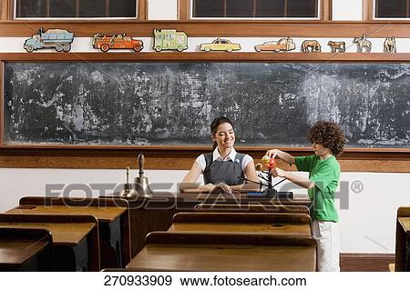 Schoolboy and his teacher with model of solar system in a classroom View Large Photo Image Stock Photo - Schoolboy and his teacher with model of solar system in a classroom. Fotosearch