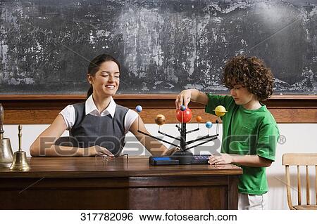Schoolboy and his teacher with model of solar system in a classroom View Large Photo Image Stock Photograph - Schoolboy and his teacher with model of solar system in a classroom. Fotosearch