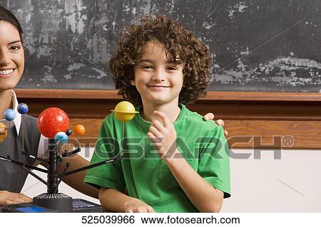Schoolboy and his teacher with model of solar system in a classroom View Large Photo Image Stock Photograph - Schoolboy and his teacher with model of solar system in a classroom. Fotosearch
