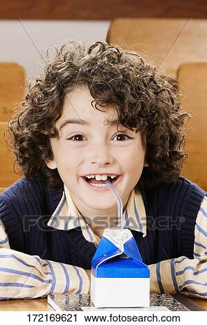 Stock Image - Schoolboy drinking juice in a classroom. Fotosearch