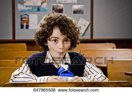 Schoolboy drinking juice in a classroom View Large Photo Image Stock Photo - Schoolboy drinking juice in a classroom. Fotosearch