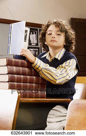 Schoolboy holding a book in a classroom View Large Photo Image Stock Image - Schoolboy holding a book in a classroom. Fotosearch