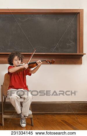 Stock Photography - Schoolboy playing a violin in a classroom. Fotosearch