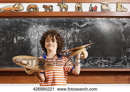Stock Image - Schoolboy playing cymbals in a classroom. Fotosearch