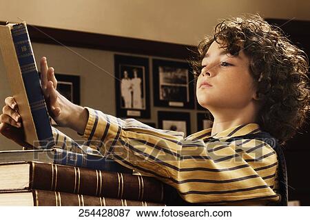 Stock Photo - Schoolboy reading a book in a classroom. Fotosearch