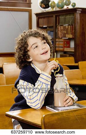 Schoolboy sitting in a classroom with chocolate milkshake bottle View Large Photo Image Stock Image - Schoolboy sitting in a classroom with chocolate milkshake bottle. Fotosearch