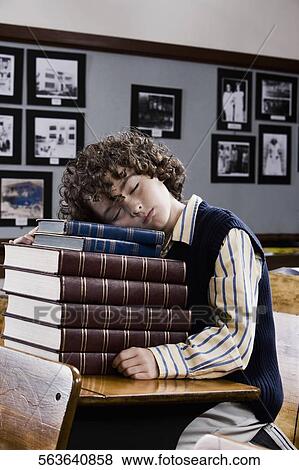Stock Photo - Schoolboy sleeping on books in a classroom. Fotosearch