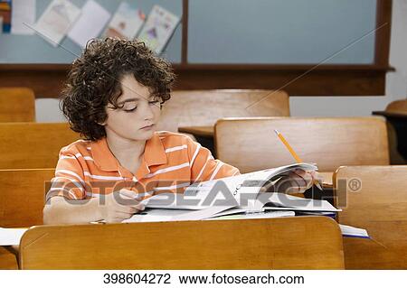 Schoolboy studying in a classroom View Large Photo Image Stock Image - Schoolboy studying in a classroom. Fotosearch