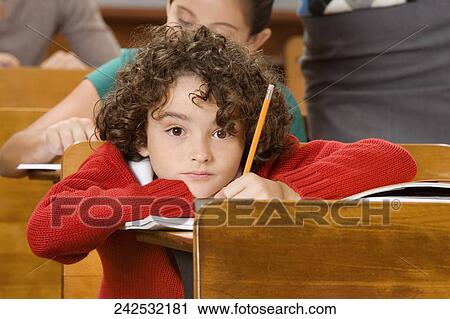 Schoolboy thinking while his classmates studying with their teacher View Large Photo Image Stock Image - Schoolboy thinking while his classmates studying with their teacher. Fotosearch