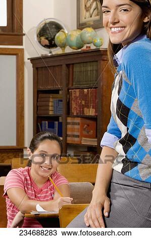 Stock Image - Schoolgirl and her teacher smiling in a classroom. Fotosearch