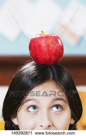 Schoolgirl balancing an apple on her head in a classroom View Large Photo Image Stock Image - Schoolgirl balancing an apple on her head in a classroom. Fotosearch