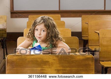 Schoolgirl drinking juice in a classroom View Large Photo Image Stock Photo - Schoolgirl drinking juice in a classroom. Fotosearch