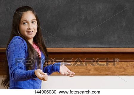 Schoolgirl gesturing in front of a blackboard View Large Photo Image Stock Image - Schoolgirl gesturing in front of a blackboard. Fotosearch