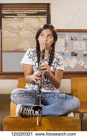 Stock Image - Schoolgirl playing a clarinet in a classroom. Fotosearch