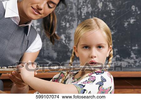 Schoolgirl playing a flute in a classroom View Large Photo Image Picture - Schoolgirl playing a flute in a classroom. Fotosearch