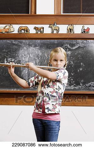 Schoolgirl playing a flute in a classroom View Large Photo Image Stock Photograph - Schoolgirl playing a flute in a classroom. Fotosearch
