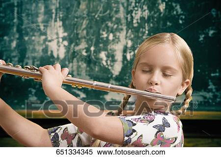 Stock Photography - Schoolgirl playing a flute in front of a blackboard. Fotosearch