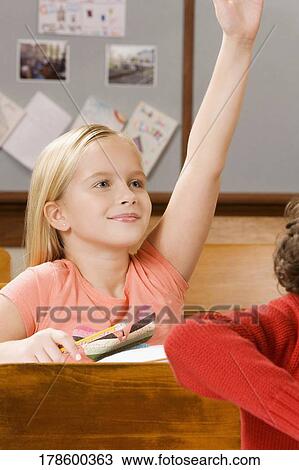 Schoolgirl raising her hand in a classroom View Large Photo Image Stock Image - Schoolgirl raising her hand in a classroom. Fotosearch