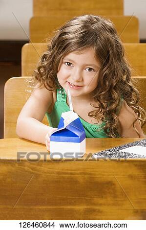 Schoolgirl sitting with a juice packet in a classroom View Large Photo Image Picture - Schoolgirl sitting with a juice packet in a classroom. Fotosearch