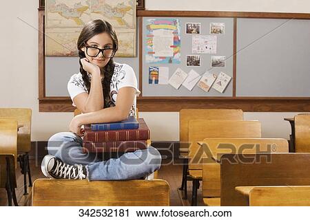Schoolgirl smiling in a classroom View Large Photo Image Stock Image - Schoolgirl smiling in a classroom. Fotosearch