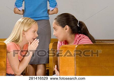 Schoolgirl whispering to her friend in a classroom View Large Photo Image Stock Photo - Schoolgirl whispering to her friend in a classroom. Fotosearch