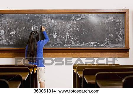 Schoolgirl writing on a blackboard in a classroom View Large Photo Image Picture - Schoolgirl writing on a blackboard in a classroom. Fotosearch