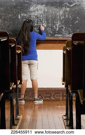 Schoolgirl writing on a blackboard in a classroom View Large Photo Image Stock Image - Schoolgirl writing on a blackboard in a classroom. Fotosearch