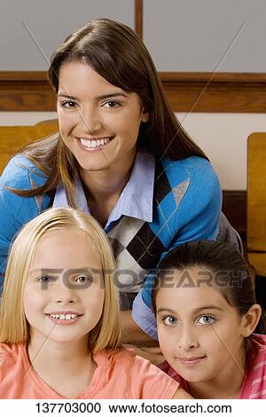 Schoolgirls and their teacher smiling in a classroom View Large Photo Image Stock Image - Schoolgirls and their teacher smiling in a classroom. Fotosearch
