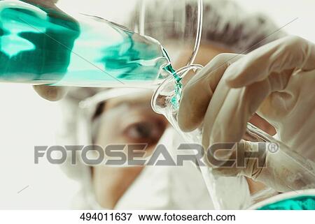 Scientist pouring liquid into a conical flask View Large Photo Image Stock Photo - Scientist pouring liquid into a conical flask. Fotosearch