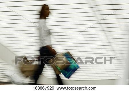 Side profile of a woman carrying shopping bags View Large Photo Image Stock Photo - Side profile of a woman carrying shopping bags. Fotosearch