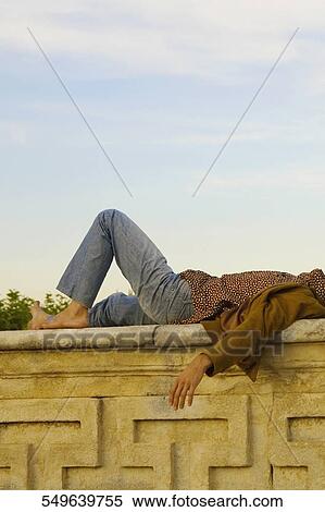 Side profile of a young man lying on a stone wall View Large Photo Image Stock Photography - Side profile of a young man lying on a stone wall. Fotosearch