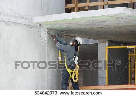 Side view of a construction worker working inside a building View Large Photo Image Stock Image - Side view of a construction worker working inside a building. Fotosearch