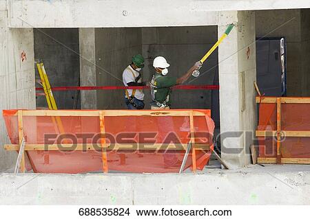 Side view of two construction workers at a construction site View Large Photo Image Picture - Side view of two construction workers at a construction site. Fotosearch