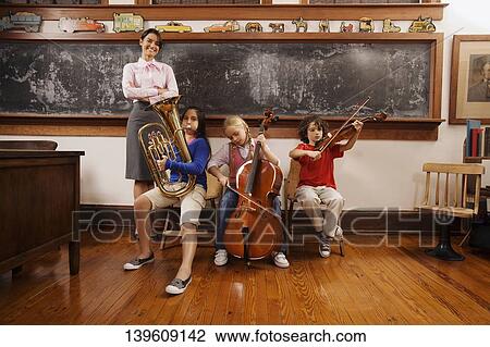 Students playing musical instruments with their teacher standing beside them View Large Photo Image Stock Image - Students playing musical instruments with their teacher standing beside them. Fotosearch