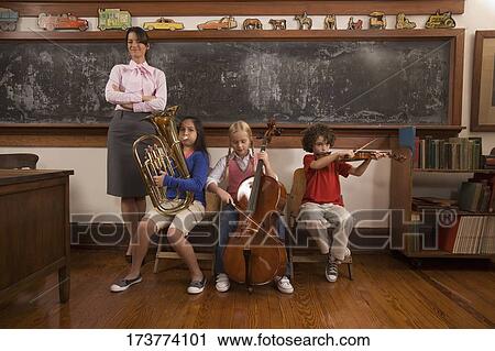 Students playing musical instruments with their teacher standing beside them View Large Photo Image Stock Image - Students playing musical instruments with their teacher standing beside them. Fotosearch