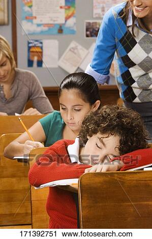 Students studying with a schoolboy sleeping in a classroom View Large Photo Image Stock Image - Students studying with a schoolboy sleeping in a classroom. Fotosearch