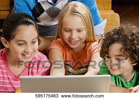 Students with their teacher using a laptop in a classroom View Large Photo Image Stock Image - Students with their teacher using a laptop in a classroom. Fotosearch