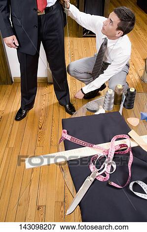 Tailor taking measurement of a businessman View Large Photo Image Stock Photo - Tailor taking measurement of a businessman. Fotosearch
