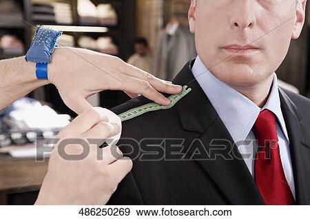 Tailor taking measurement of a businessman View Large Photo Image Stock Photo - Tailor taking measurement of a businessman. Fotosearch
