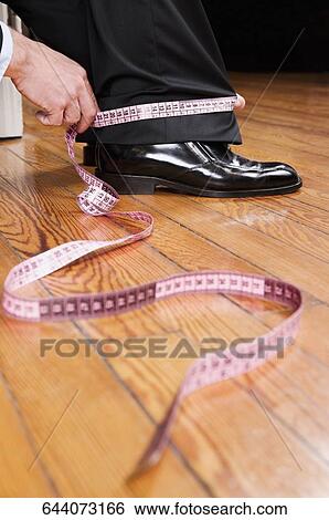 Tailor taking measurement of a businessman View Large Photo Image Stock Photograph - Tailor taking measurement of a businessman. Fotosearch