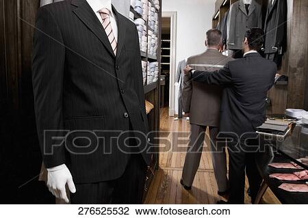 Stock Image - Tailor taking the measurements of a customer. Fotosearch