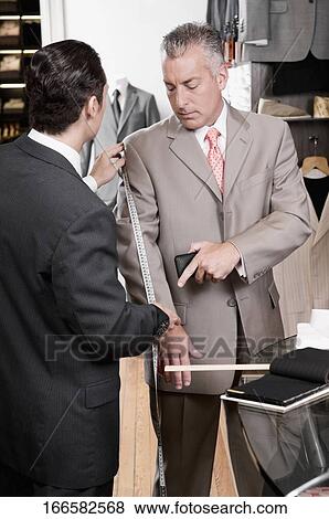 Tailor taking the measurements of a customer View Large Photo Image Stock Photo - Tailor taking the measurements of a customer. Fotosearch