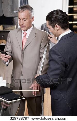 Tailor taking the measurements of a customer View Large Photo Image Stock Photo - Tailor taking the measurements of a customer. Fotosearch