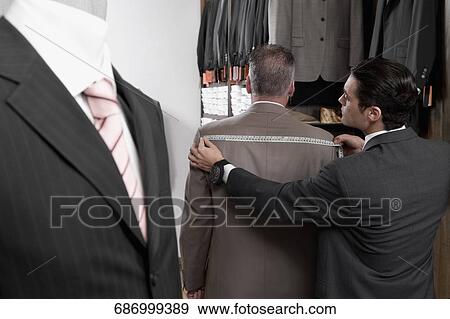 Tailor taking the measurements of a customer View Large Photo Image Stock Photo - Tailor taking the measurements of a customer. Fotosearch