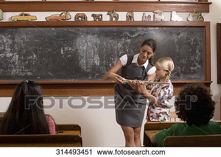 Teacher assist a schoolgirl playing a flute in a classroom View Large Photo Image Stock Image - Teacher assist a schoolgirl playing a flute in a classroom. Fotosearch