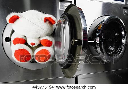 Picture - Teddy bear in a washing machine in a laundromat. Fotosearch