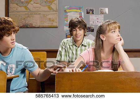 Stock Image - Teenage boy convincing his friend in the classroom. Fotosearch