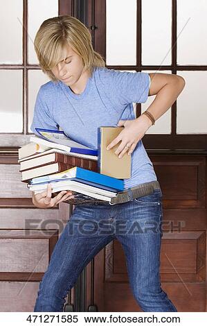 Teenage boy holding books in a school corridor View Large Photo Image Stock Photography - Teenage boy holding books in a school corridor. Fotosearch