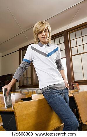 Teenage boy leaning against a chair in a classroom View Large Photo Image Stock Photo - Teenage boy leaning against a chair in a classroom. Fotosearch